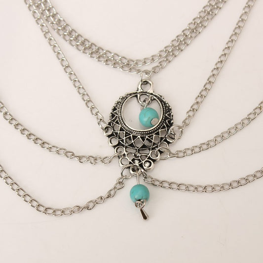 Multiple silver necklaces with turquoise beads on a light background