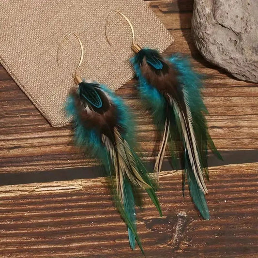 Feather earrings on a wooden surface with a stone and fabric background