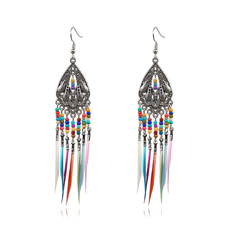 Multicolored feather earrings with intricate metalwork on a white background