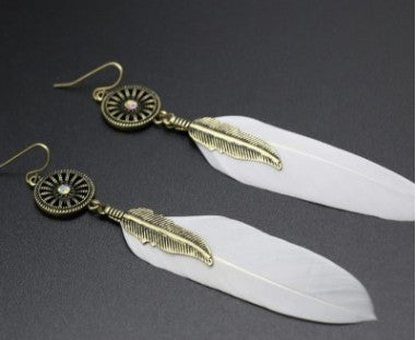 Feather earrings with gold and bronze detailing on a dark background