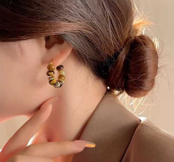 Close-up of a person wearing a pair of beaded earrings with a neutral background from nested wisdom