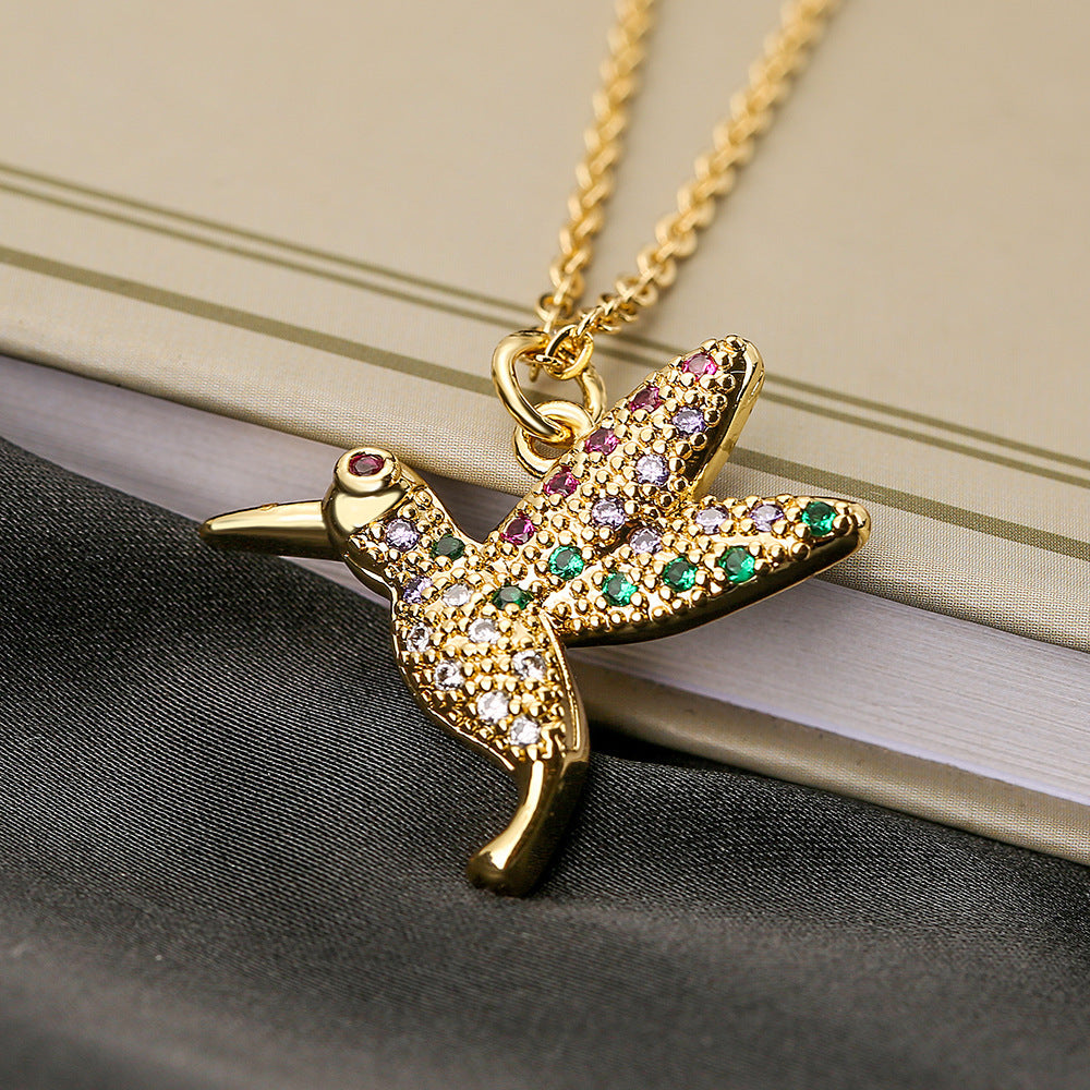 Gold necklace with a starfish pendant featuring colorful gemstones on a textured surface.