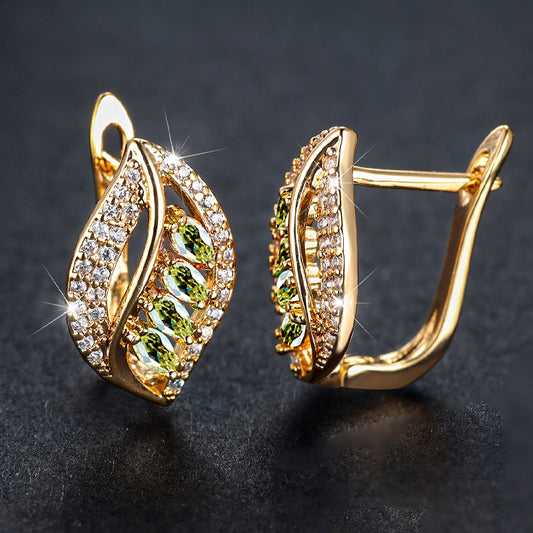 Gold earrings with green gemstones on a dark background