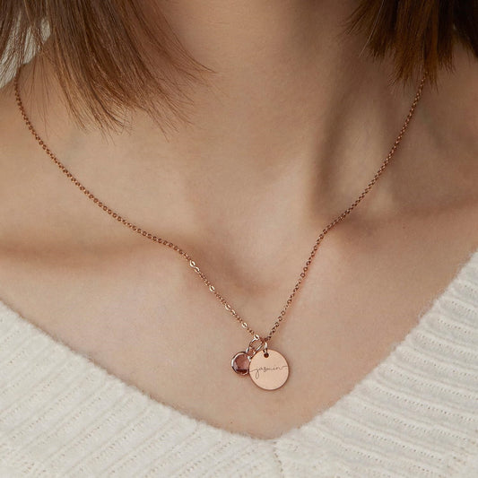 Rose gold necklace with circular pendants on a person wearing a white sweater.