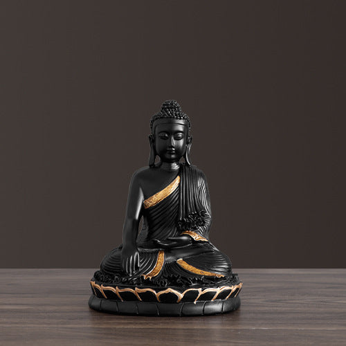 Black and gold Buddha statue on a wooden surface with a dark brown background