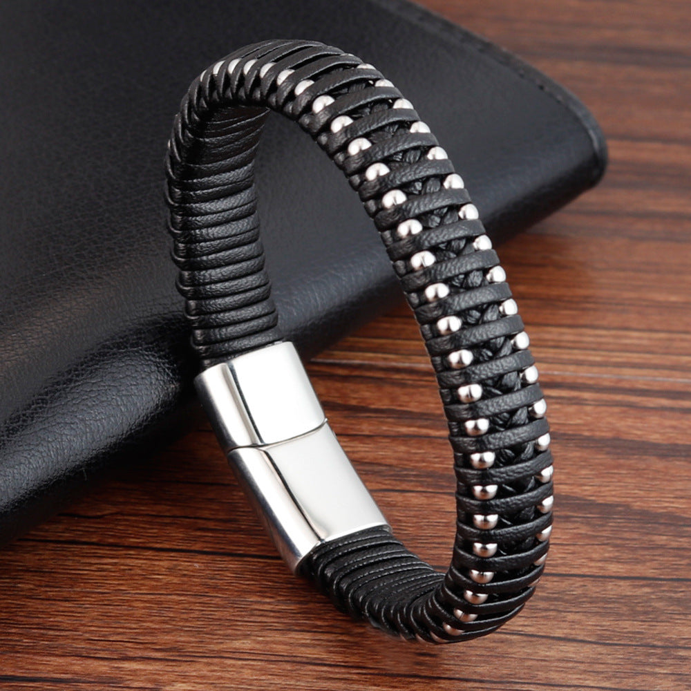Black braided leather bracelet with silver clasp on a wooden surface