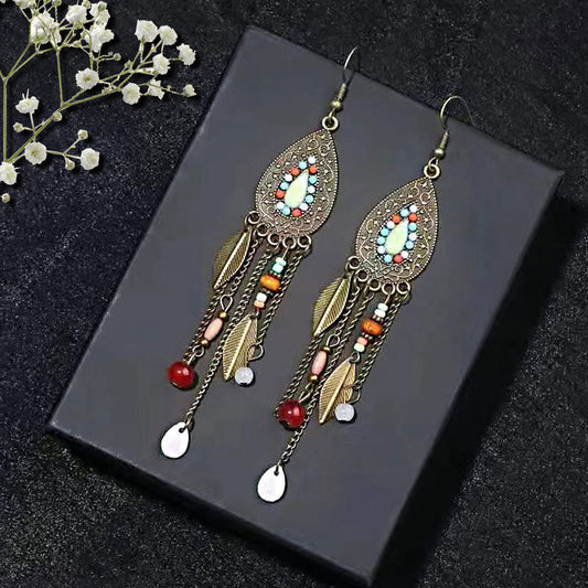 Bohemian-Tribal-Fringe-Earrings-Ornate earrings with colorful beads on a dark surface with flowers.