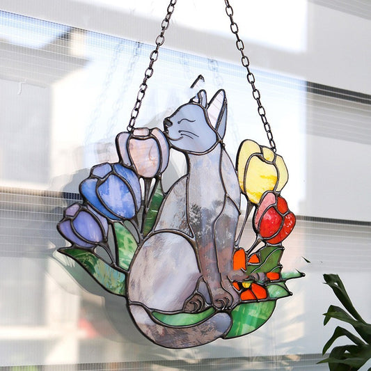 Stained glass panel of a cat among flowers hanging on a window