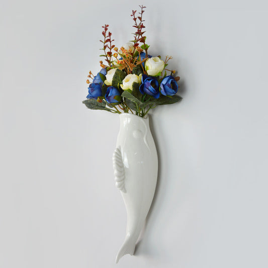 White fish-shaped vase with artificial flowers on a light gray background