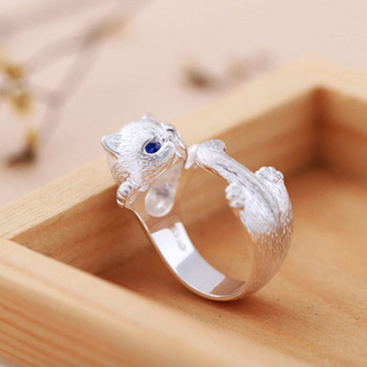 Silver cat-shaped ring with a blue gemstone on a wooden surface