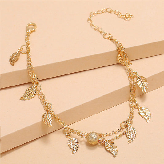 Gold necklace with leaf charms on a beige background