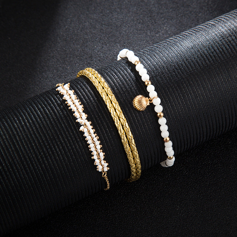 Three gold and pearl bracelets on a black textured surface