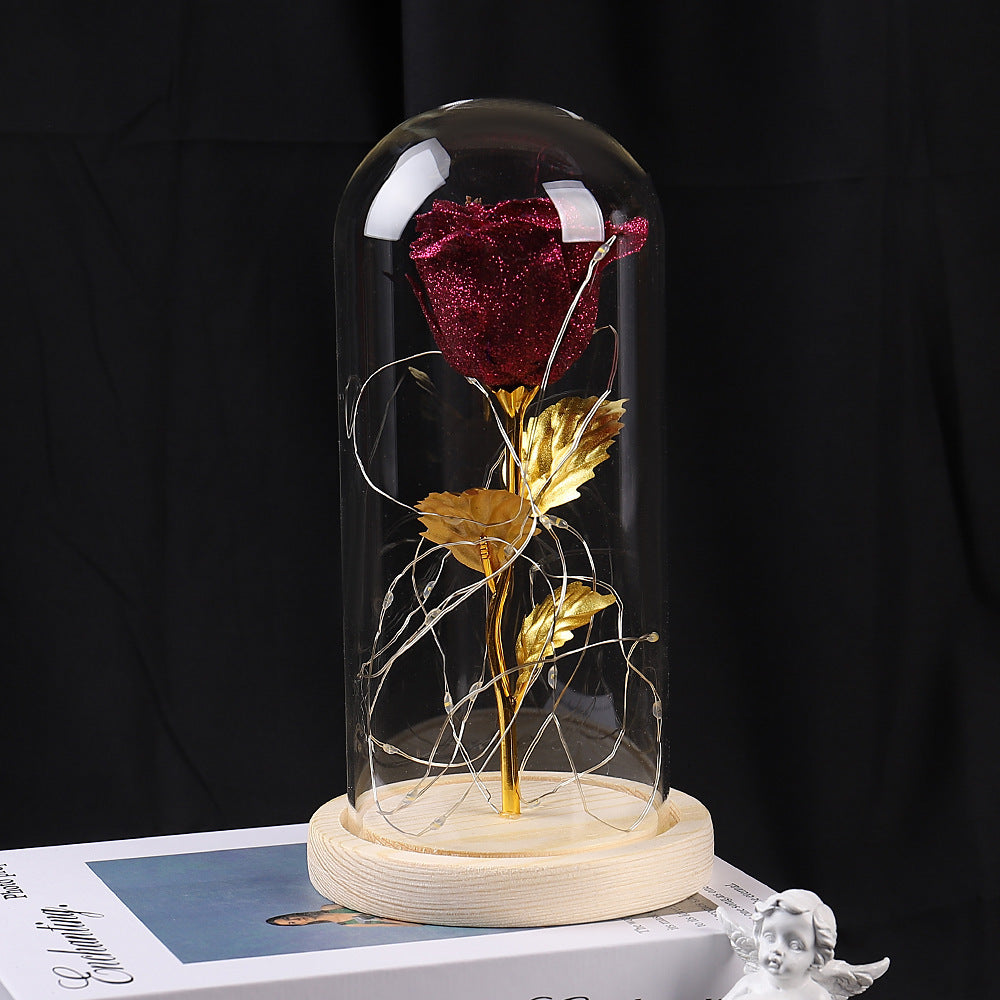 Red rose with gold leaves under a glass dome on a black background