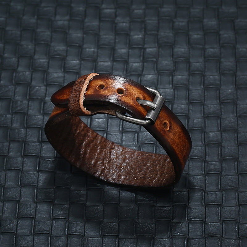 Brown leather bracelet with a silver clasp on a textured black background
