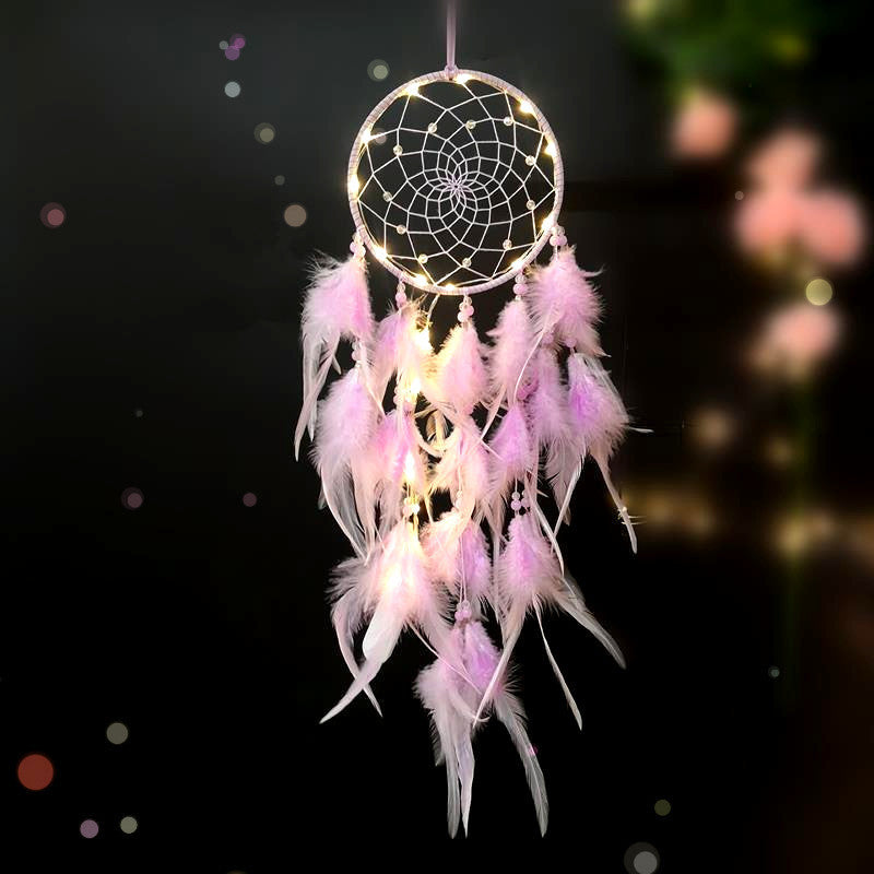 Decorative dreamcatcher with pink feathers and LED lights on a dark background