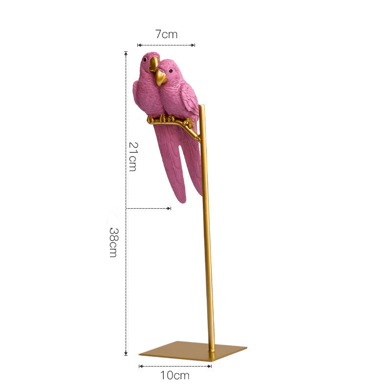 Pink parrot figurine on a gold perch with measurements on a white background