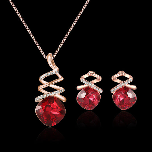 Jewelry set with red gemstones and rose gold accents on a black background