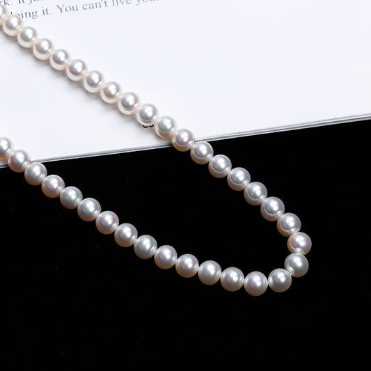 Pearl necklace on a black surface with a white background