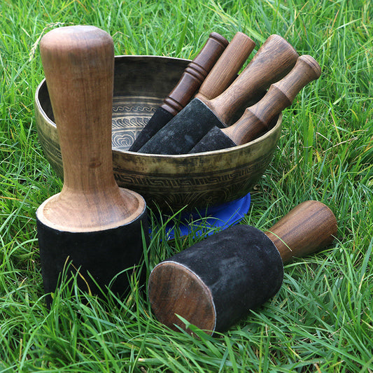 Tibetan singing bowl set with wooden handles on grass