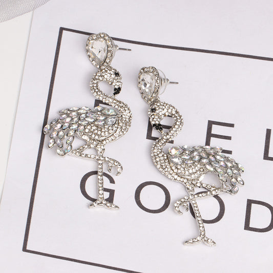 Flamingo-shaped earrings with rhinestones on a white background