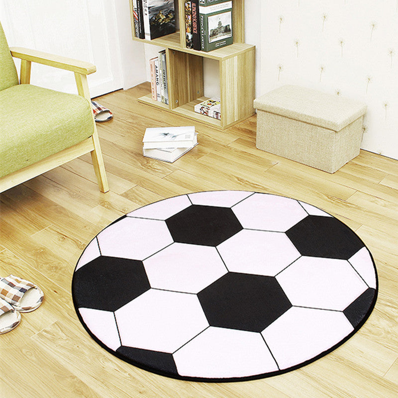 Round soccer ball rug on a wooden floor with a bookshelf and chair in the background.