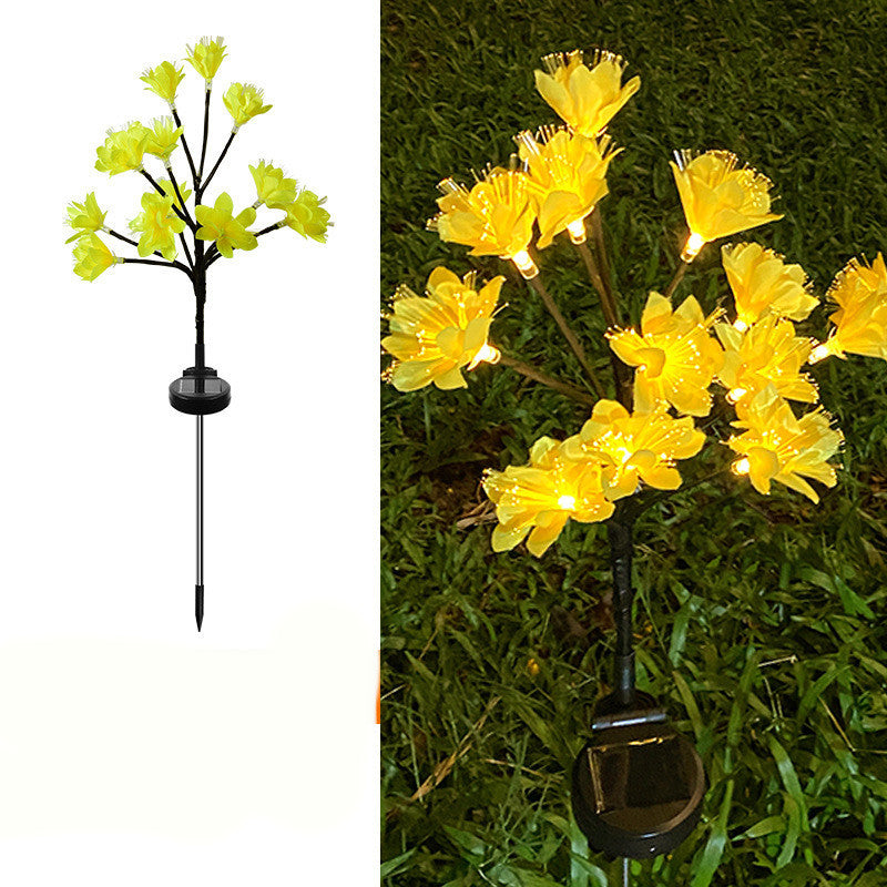 Solar-powered yellow flower light on a white background and in outdoor grass.