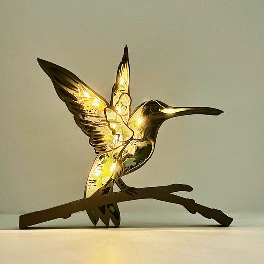 Decorative hummingbird light on a branch against a plain background