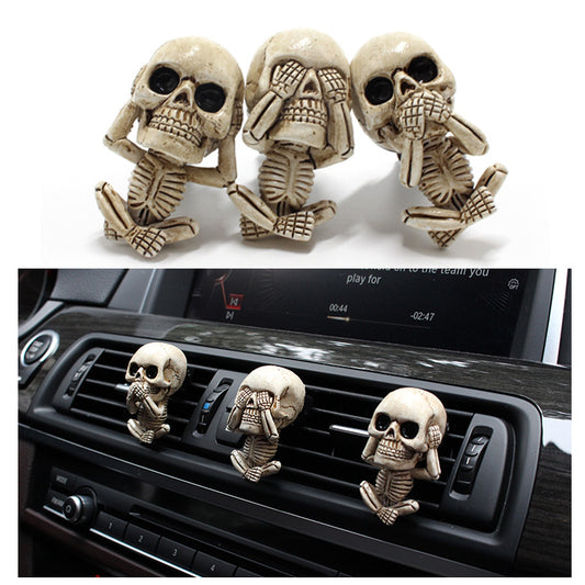 Skull-shaped car air freshener set with 'see no evil, hear no evil, speak no evil' poses on a white background.
