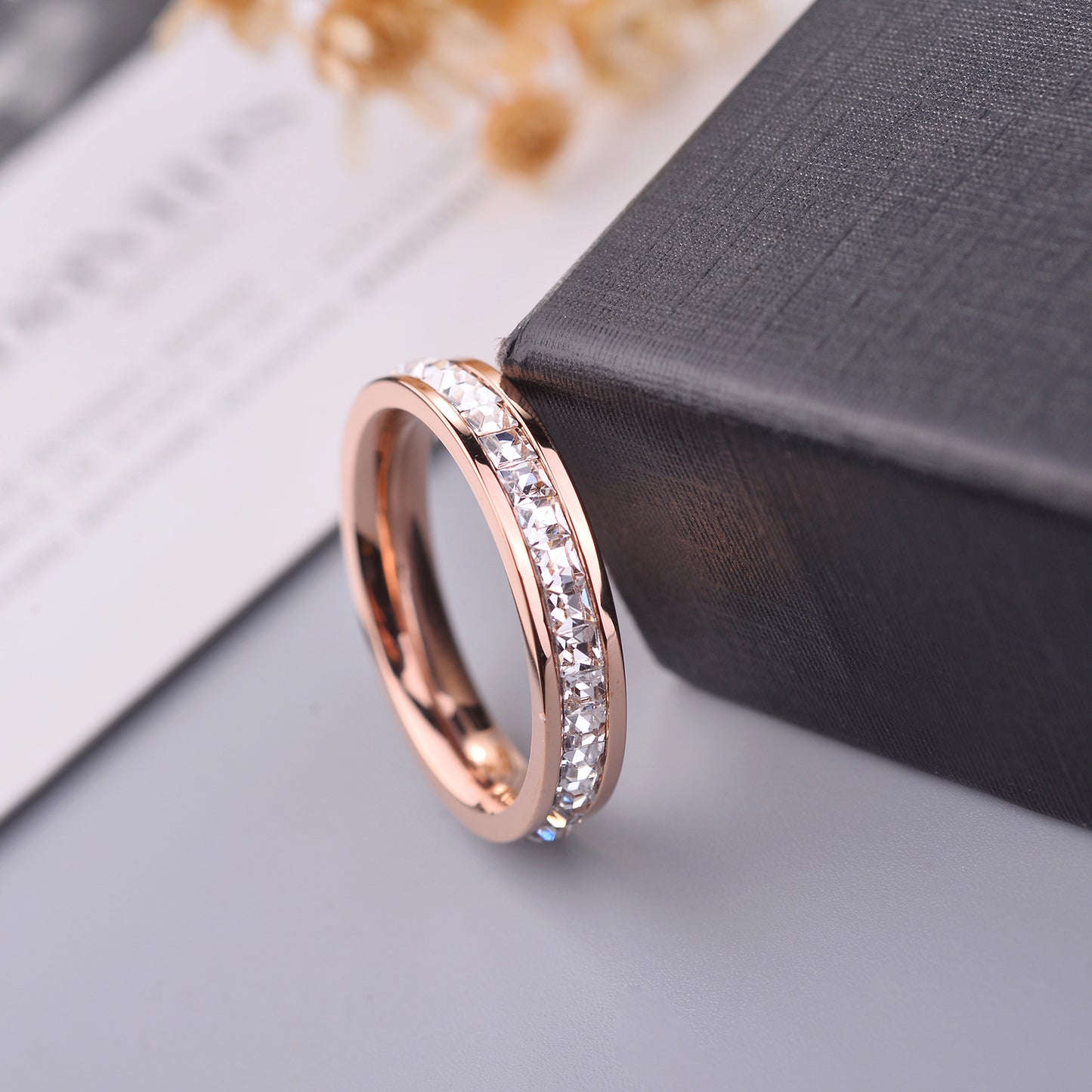Rose gold ring with embedded diamonds on a gray surface