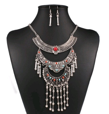 Silver necklace with red and blue stones on a black mannequin bust.