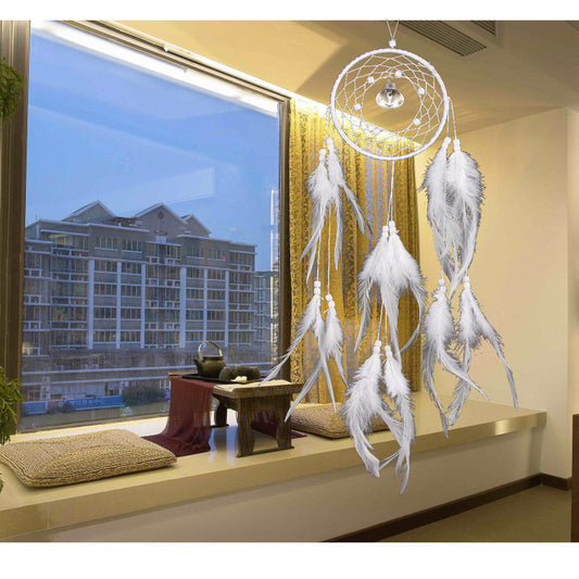 White dreamcatcher with feathers hanging in a room with large windows.