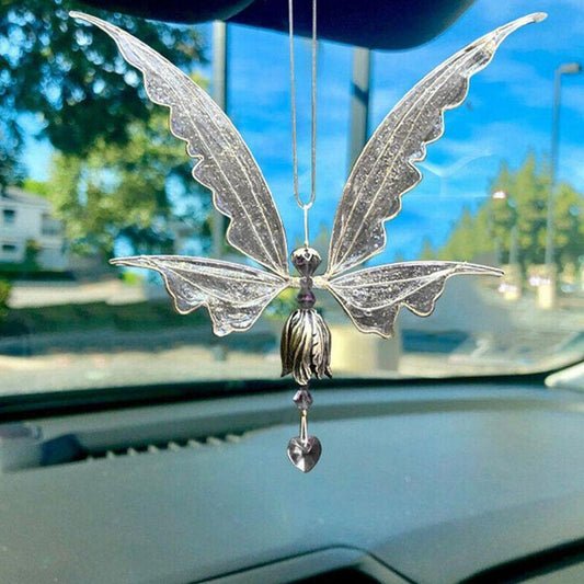 Decorative butterfly car hanging on a car's rearview mirror with a blurred outdoor background.