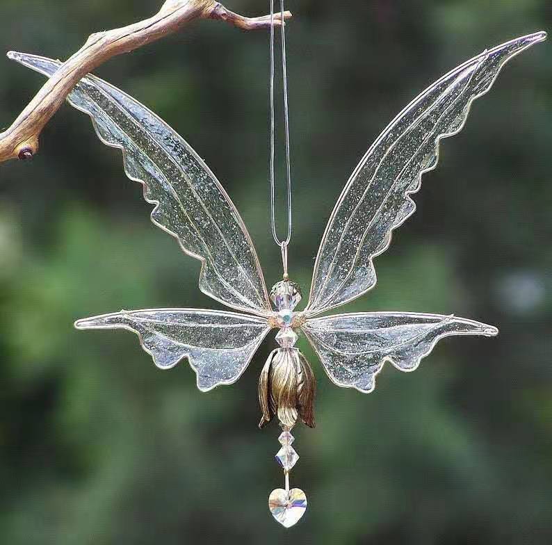Decorative butterfly ornament with clear wings and gemstone details on a branch.