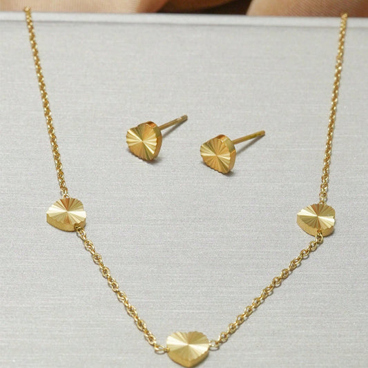 Gold necklace and earrings on a light gray background
