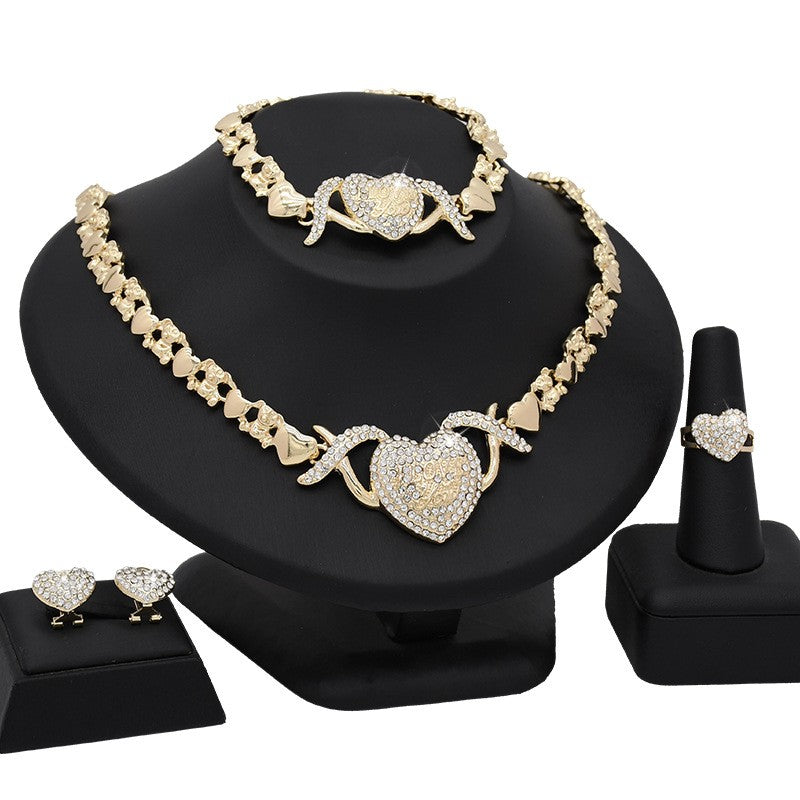 Jewelry set with necklace, bracelet, earrings, and ring on a black stand.