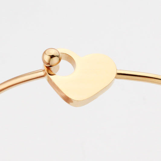 Gold heart-shaped bangle on a light gray background