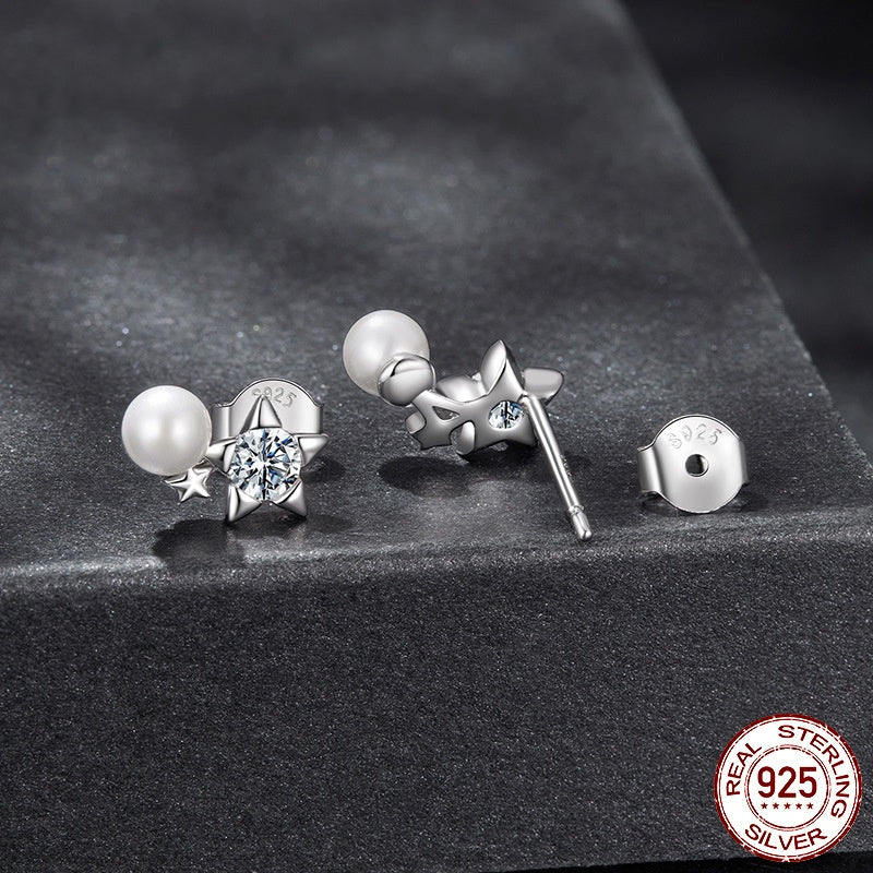 Set of silver earrings with pearls and gemstones on a dark surface, featuring 'Real Sterling 925' stamp.