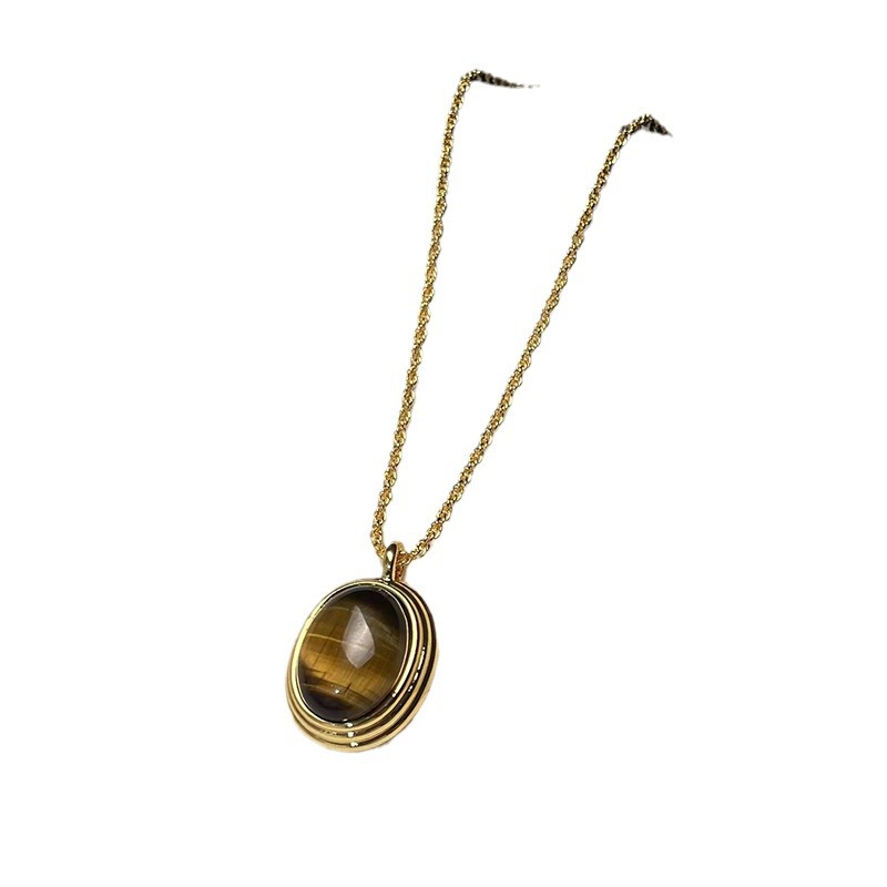 Gold necklace with a tiger's eye pendant on a white background
