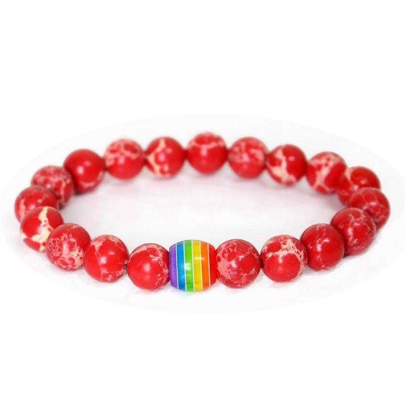 Red beaded bracelet with a rainbow heart charm on a white background