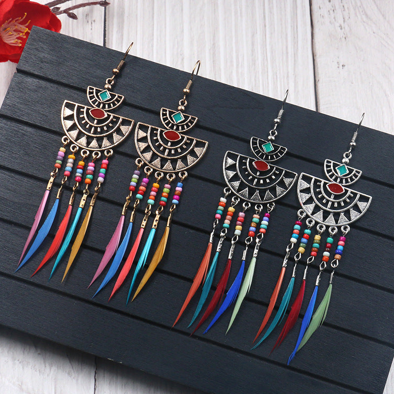 Pair of colorful feather earrings on a dark wooden surface