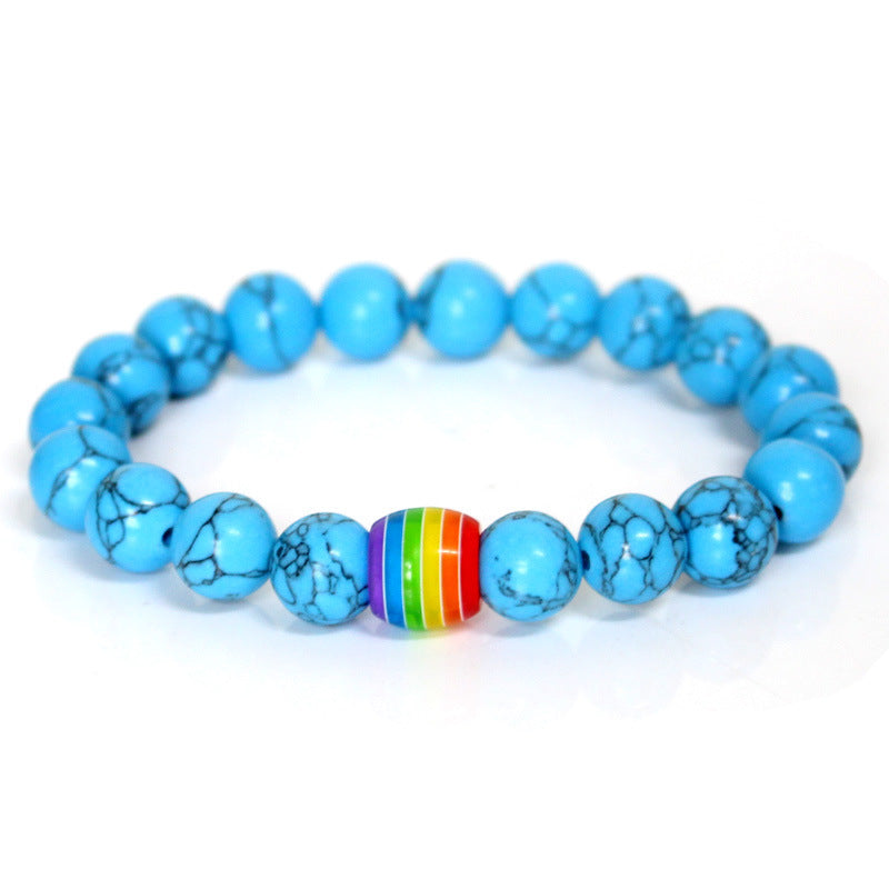 Turquoise beaded bracelet with a rainbow central bead on a white background