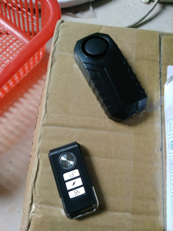 Two black electronic devices on a cardboard surface with a red basket in the background.