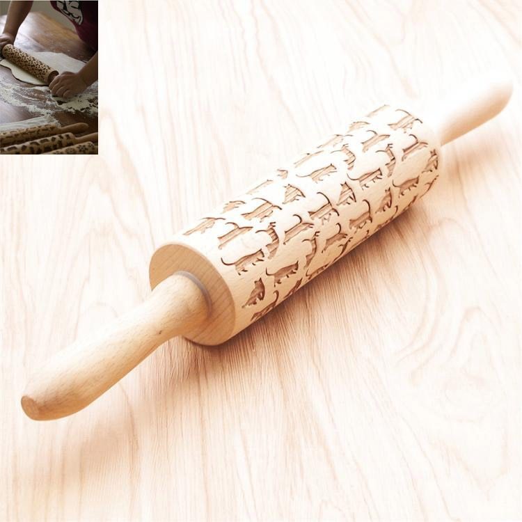 Wooden rolling pin with embossed designs on a light wooden surface.