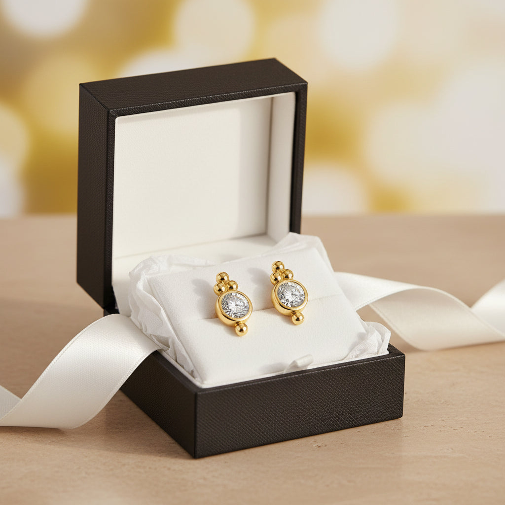 Gold earrings with round gemstones in a gift box