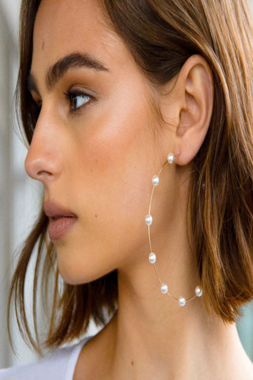 Close-up of a woman wearing pearl earrings with a blurred background