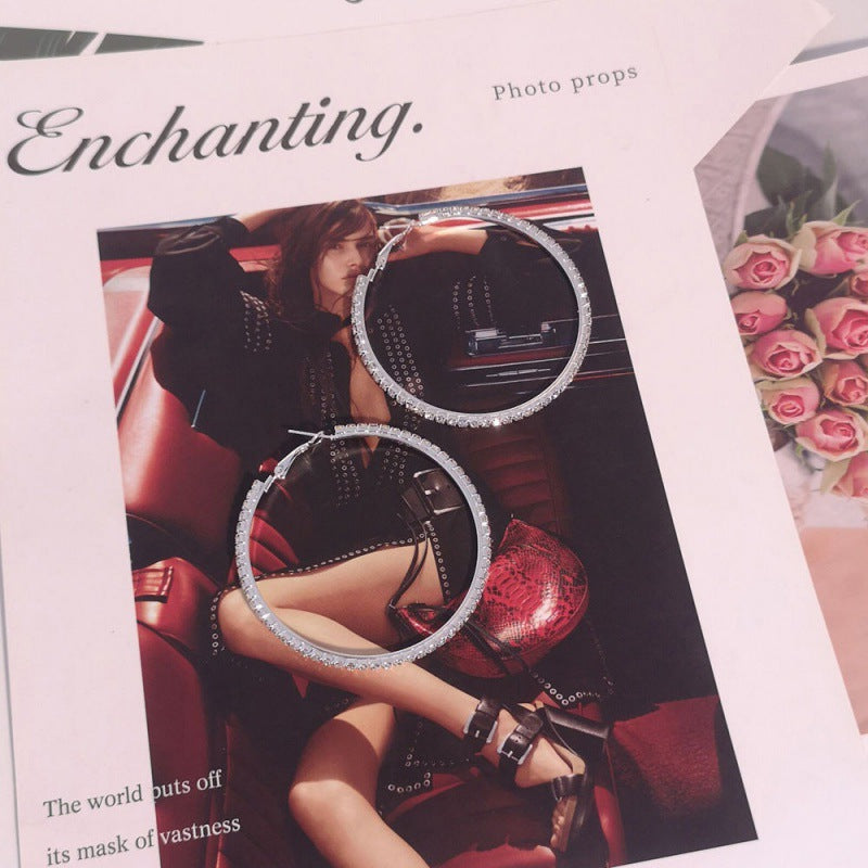Earrings displayed over a magazine with text and a car interior.