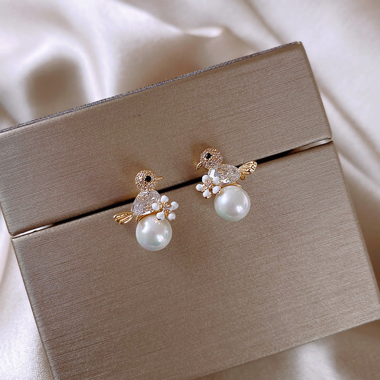 Pearl earrings on a beige jewelry box with a soft background