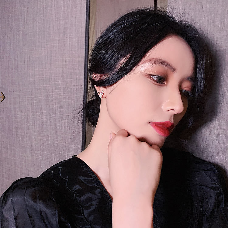 Woman with black hair and red lipstick posing against a neutral background