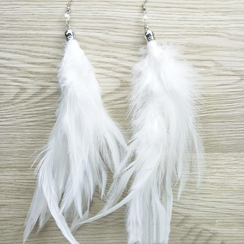 White feather earrings on a textured beige background