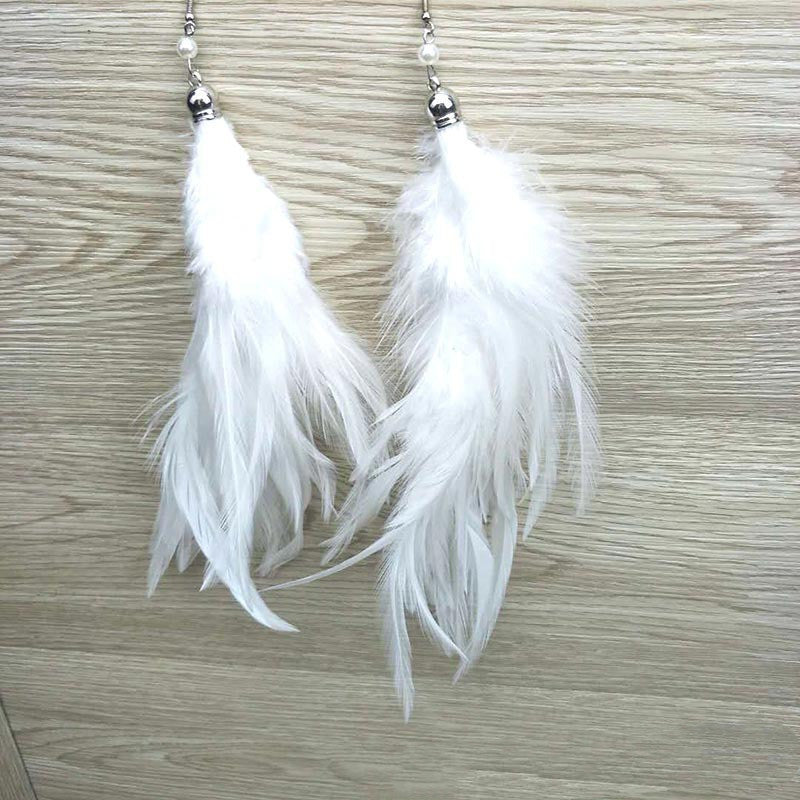 White feather earrings on a wooden surface
